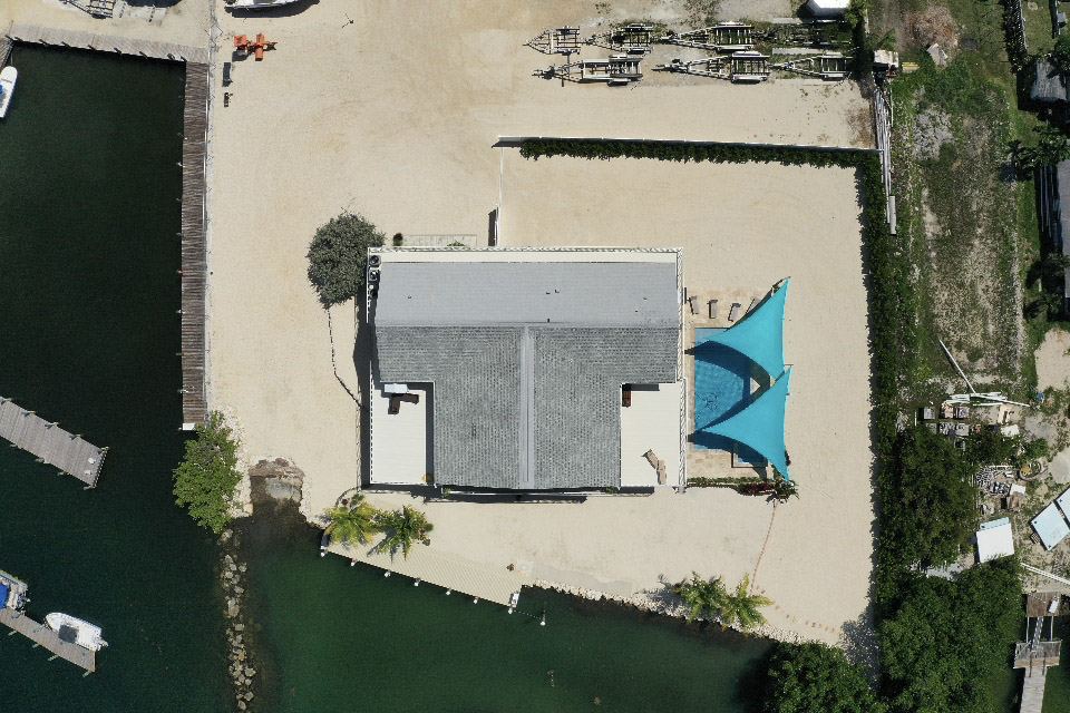 Aerial view of Dolphin Cove of Marathon with the house, pool, private beach and dock on the water