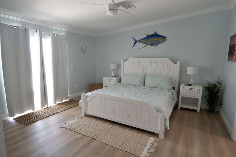 A master bedroom with a white bed and balcony doors