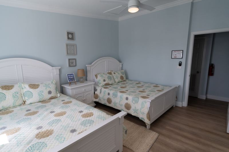 Two queen beds with nightstands and seashell-print bedding